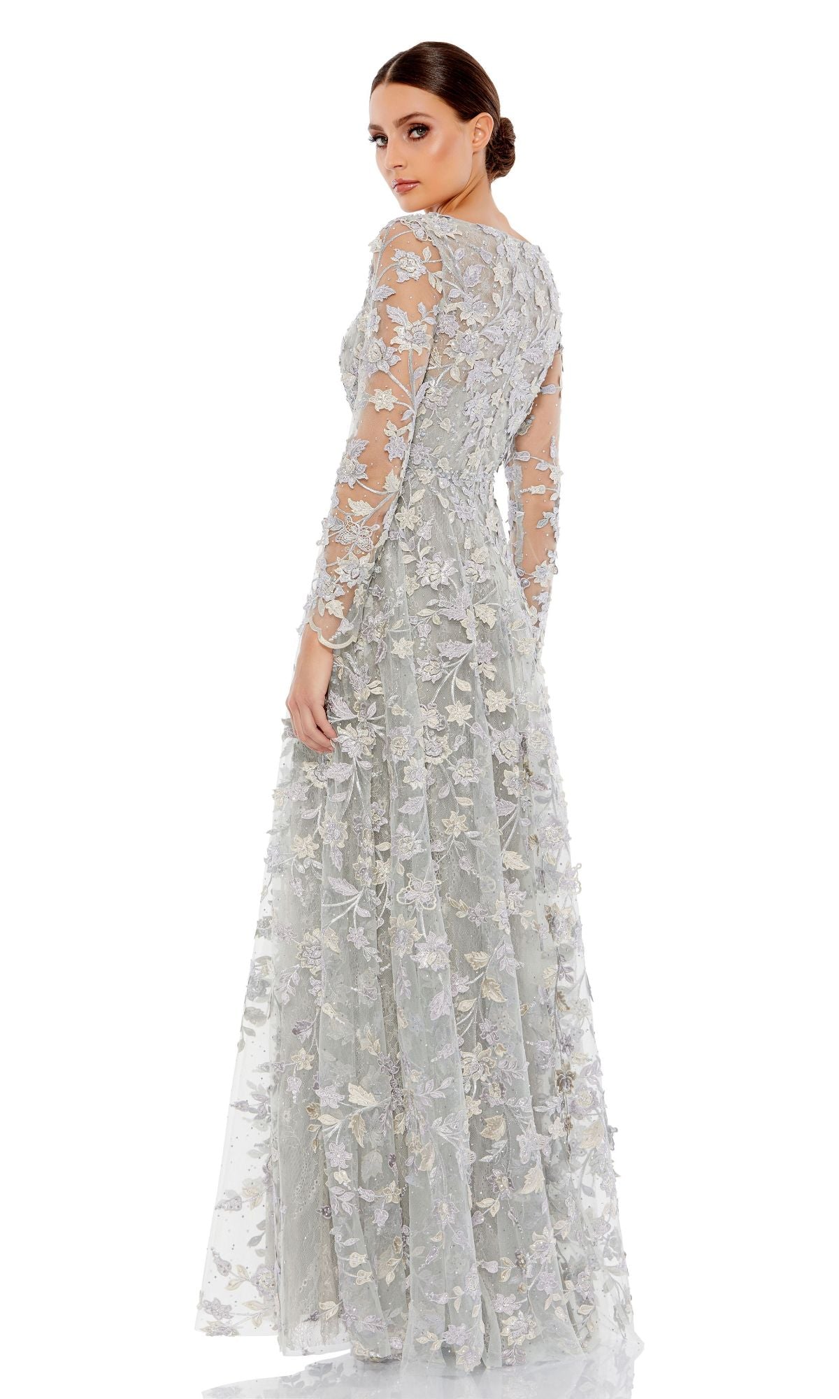 Woman posing in a Mac Duggal 70224 long sleeve formal dress with intricate floral embroidery, light gray color, standing against a plain white background.